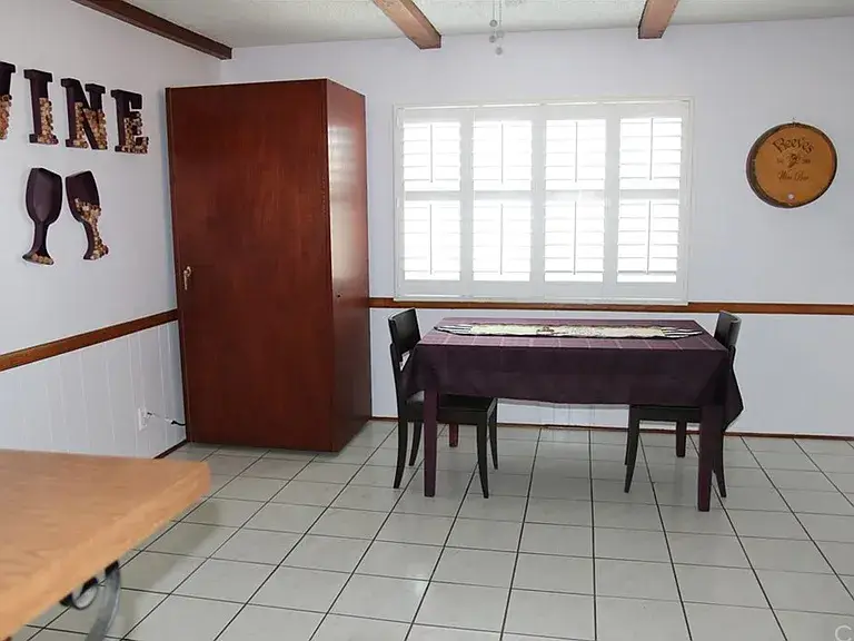 Dining room with table, chairs, tiled floor, cabinet, and wine-themed wall decor.