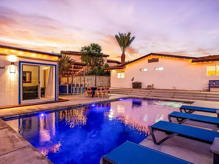 Modern backyard with pool, lounge chairs, bar area, and sunset views.